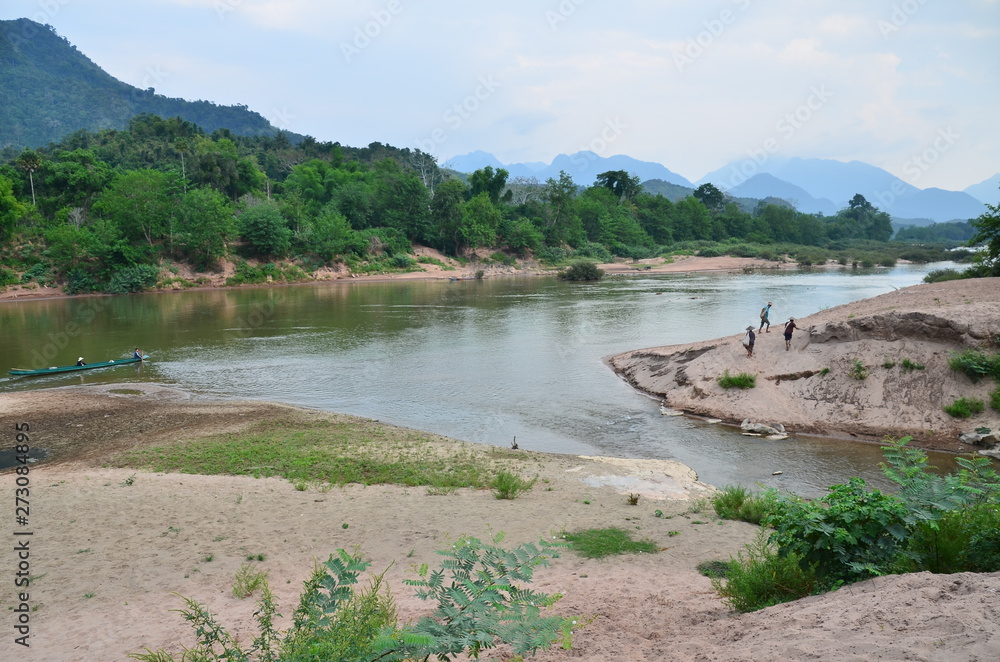 ラオス北部のノンキャウ 美しいウー川と森林 川を歩く村人 StockFoto Adobe Stock