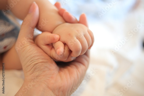 parent holding baby hands. small infant hands covered in father hand. love, care, support and comfort concepts. peaceful and loving family memory image. © suebsiri