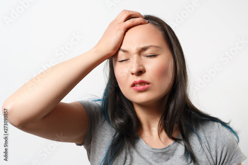 young girl grabs her head with her hand and depicts a severe headache. On white background