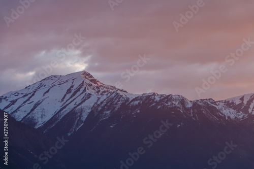 Snowy mountain with stormy red sunset sky
