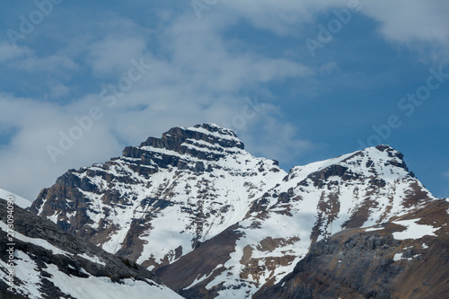 Partially snow covered mountain peaks with blue sky