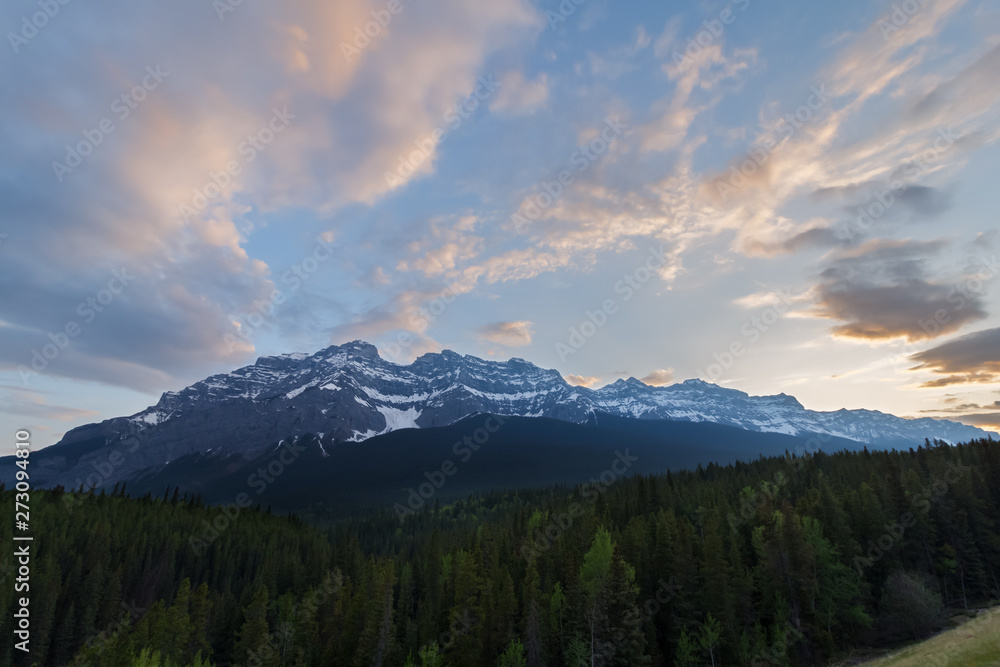 partially cloudy sunset over mountains and forest