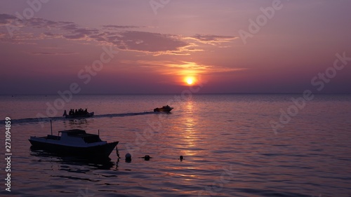 Two boats and banana boat at sunset on the purple beach
