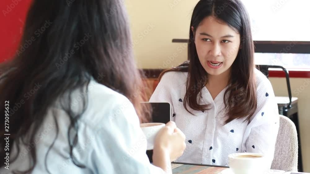 Asian woman talking together with friend in cafe
