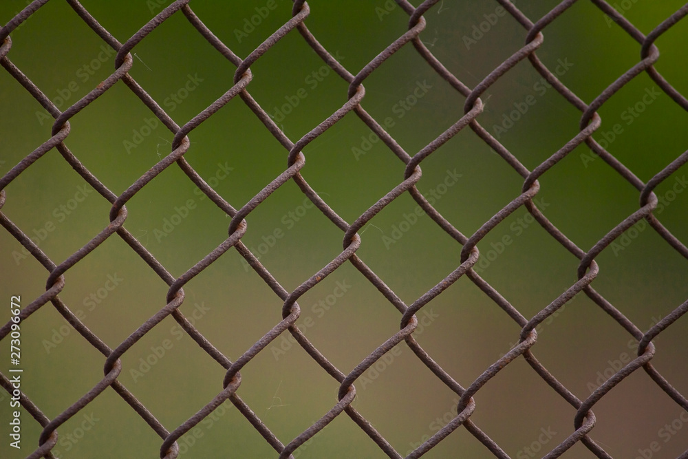 old rusty lattice on a green background. metal rusty fence old rusty lattice on a green background. metal rusty fence