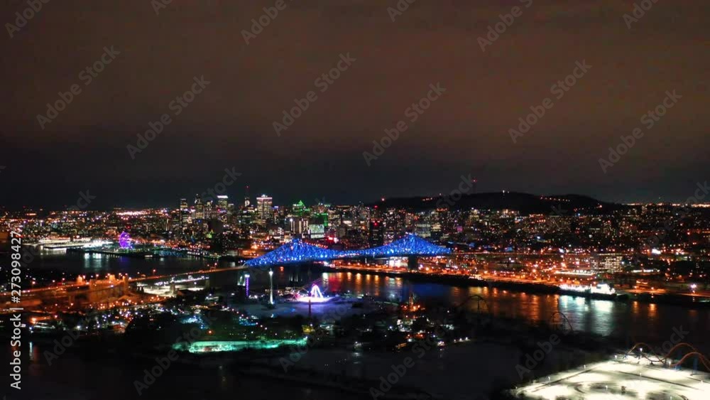 Drone flies around a large bridge at night in the winter with colorful lights in the city. Drone flies around a large bridge at night in the winter with colorful lights in the city.