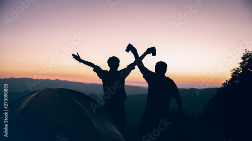 Happy time of two hiker man holding coffee cup near camping tent on mountains at sunset background. travel concept. © surachat