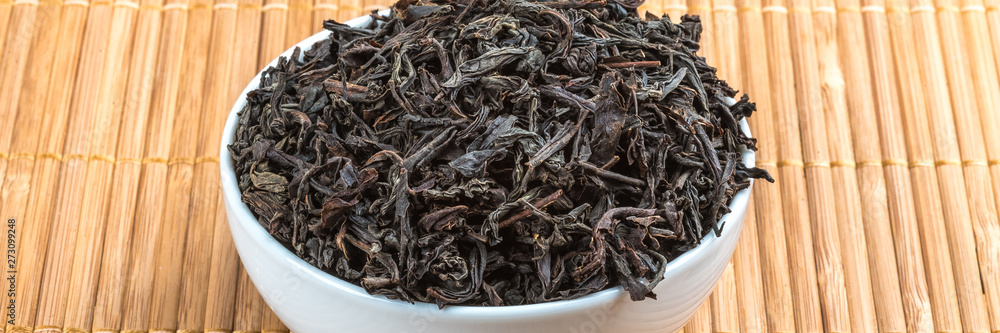 Dried tea is poured into a ceramic cup on a bamboo mat. Dried tea is poured into a ceramic cup on a bamboo mat.