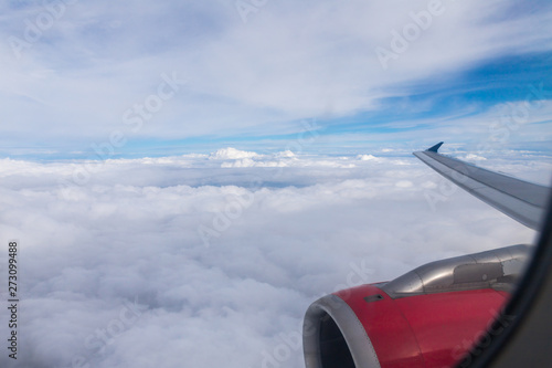 View of the clouds, the wing of the aircraft and the engine of the aircraft from the window of a flying airplane