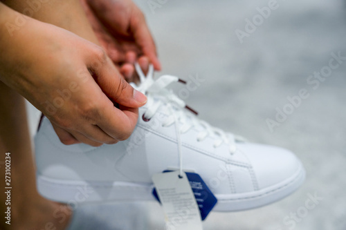 Women try new shoes in shopping mall. White sneakers stylish.