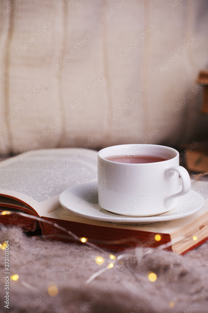 Hot tea and book with woolan plaid on wood background - seasonal relax concept. Autumn winter weekend still life background, cozy himely hygge leisure