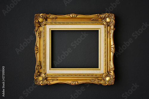 gold vintage picture frame on black color wall background, copy space, funeral and mourning concept