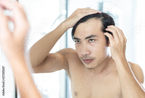 Close up man looking reflection in the mirror serious hair loss problem for health care shampoo and beauty product concept