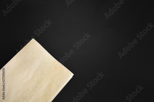 mock up of blank brown paper shopping bag isolated on black background, copy space, top view, flat lay