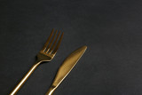 Gold fork and knife on black background. Space for text