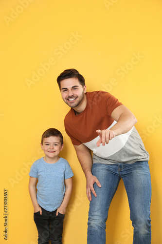 Portrait of dad and his son on color background