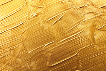 Strokes of gold paint as background, top view