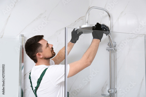 Фотография Professional handyman working in shower booth indoors