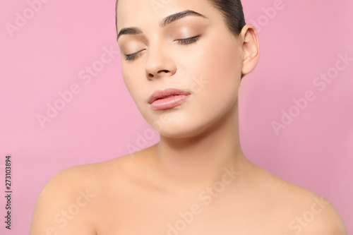 Portrait of young woman with beautiful face and natural makeup on color background, closeup