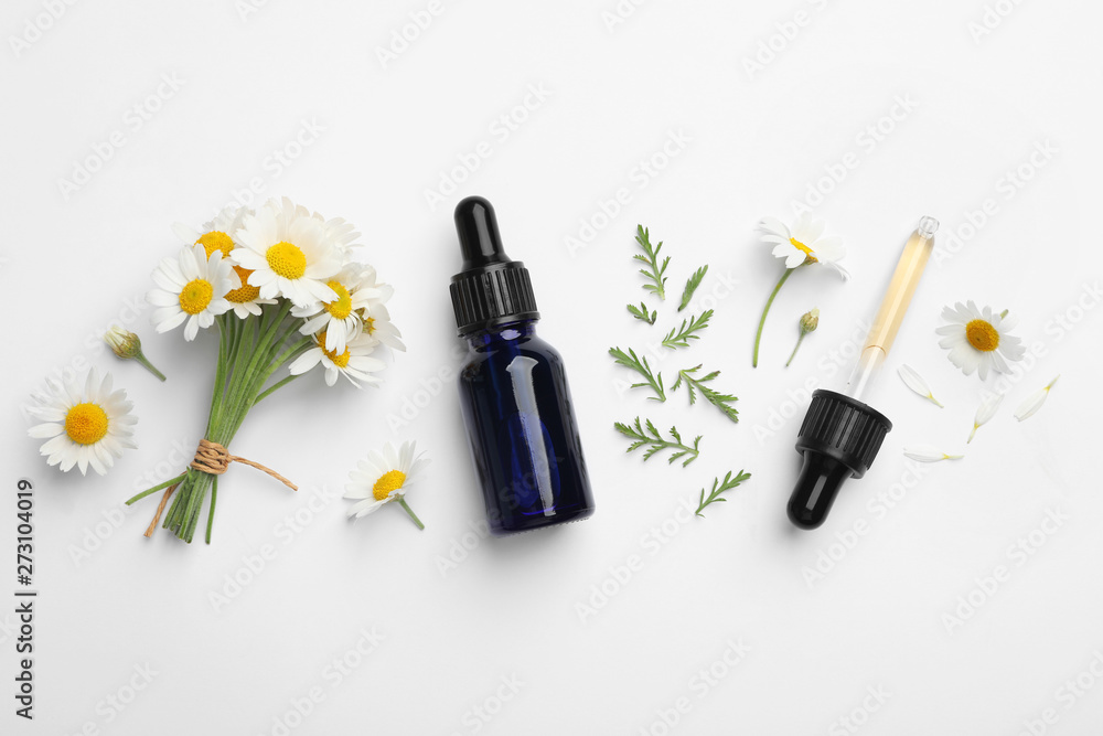 Composition with chamomile flowers and cosmetic bottle of essential oil on white background, top view - obrazy, fototapety, plakaty 