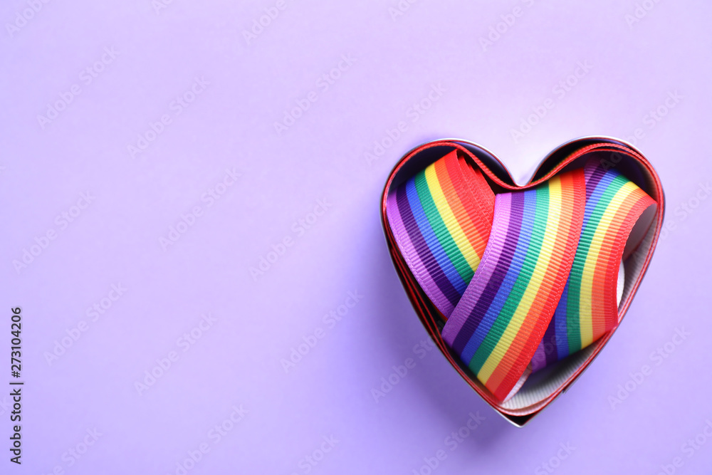 Heart shaped mold and bright rainbow ribbon on color background, top view with space for text. Symbol of gay community Heart shaped mold and bright rainbow ribbon on color background, top view with space for text. Symbol of gay community