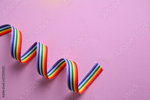 Bright rainbow ribbon on color background, top view with space for text. Symbol of gay community