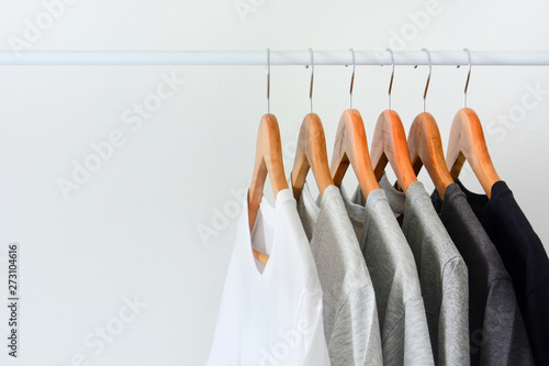 close up collection of black, gray and white color (monochrome) hanging on wooden clothes hanger in closet or clothing rack over white background, copy space