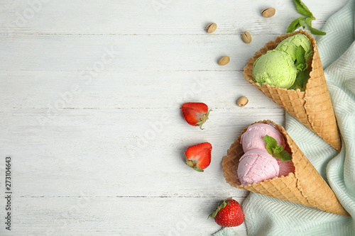 Flat lay composition with delicious ice creams in waffle cones on wooden table, space for text