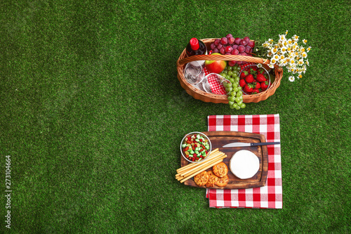 Foto Flat lay composition with picnic basket, wine and products on grass, space for t