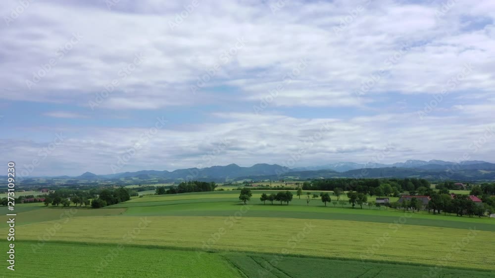 Slightly overcast summer day, drone rising over green hills with mountains in the background Slightly overcast summer day, drone rising over green hills with mountains in the background
