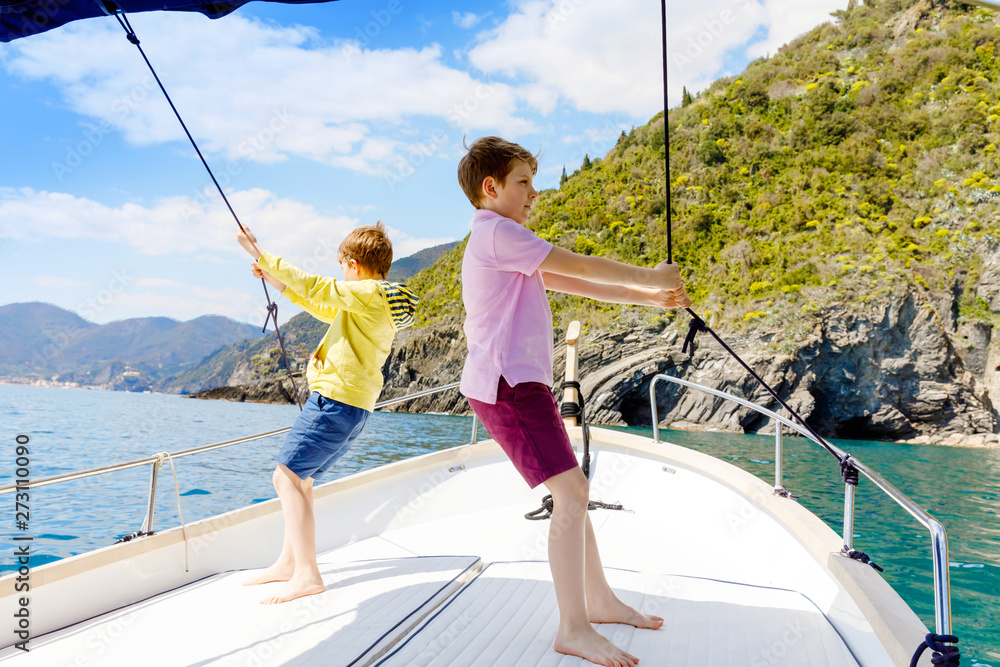 Two adorable school kid boys, best friends enjoying sailing boat trip. Family vacations on sea on sunny day. Children smiling. Brothers, schoolchilden, siblings, best friends having fun on yacht. Two adorable school kid boys, best friends enjoying sailing boat trip. Family vacations on sea on sunny day. Children smiling. Brothers, schoolchilden, siblings, best friends having fun on yacht.