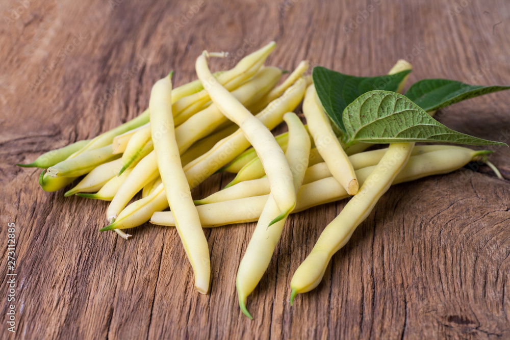 Green beans handful whit leaves on wooden background