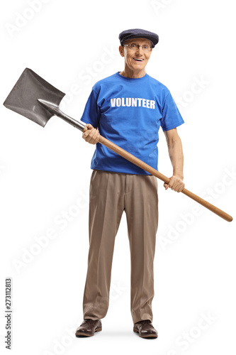 Senior volunteer in a blue t-shirt holding a shovel and looking at the camera