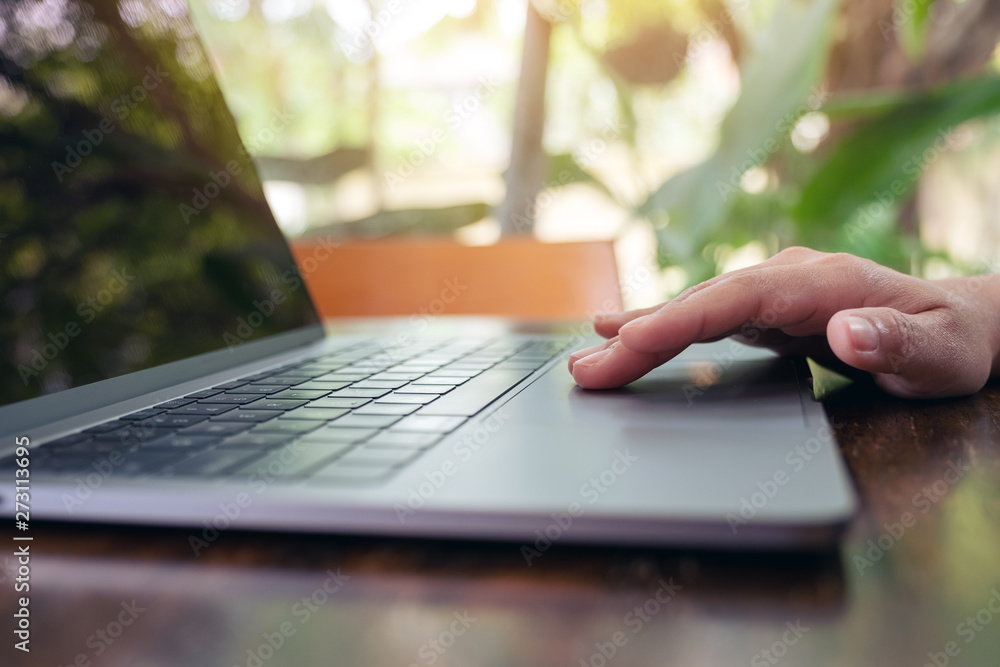 Closeup image of hand using and touching on laptop touchpad on wooden table Closeup image of hand using and touching on laptop touchpad on wooden table