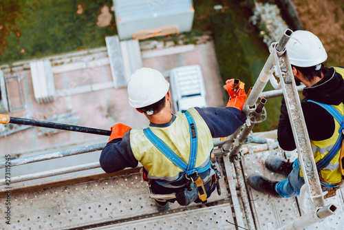 Obraz na płótnie workers work removing a scaffolding at high altitude in Oviedo, Asturias, Spain