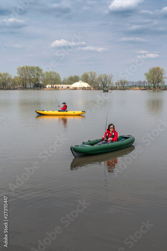 Kayak fishing at lake. Two fisherwomen on inflatable boats with fishing tackle.