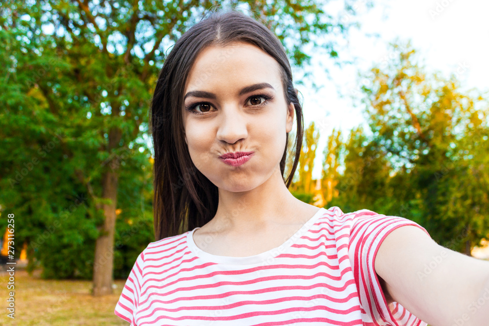 Pretty smiling girl making selfie, long-haired brunette in white clothes, closeup Pretty smiling girl making selfie, long-haired brunette in white clothes, closeup