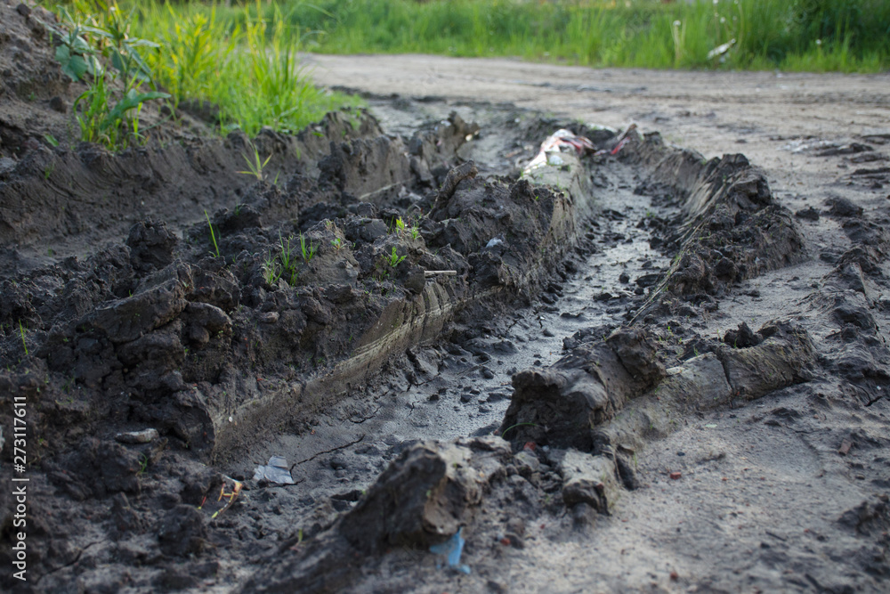 Close-up of a muddy ditch from a car wheel