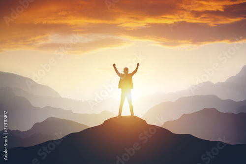 Fotografia Man standing on edge of mountain feeling victorious with arms up in the air