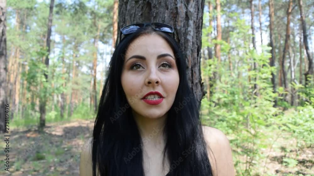 Portrait of a young brunette girl near a pine tree in the forest. Portrait of a young brunette girl near a pine tree in the forest.