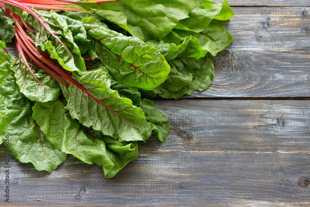 Fresh raw leaves of chard, leaf beets, mangold, swiss chard on a wooden table, close up, free space Fresh raw leaves of chard, leaf beets, mangold, swiss chard on a wooden table, close up, free space