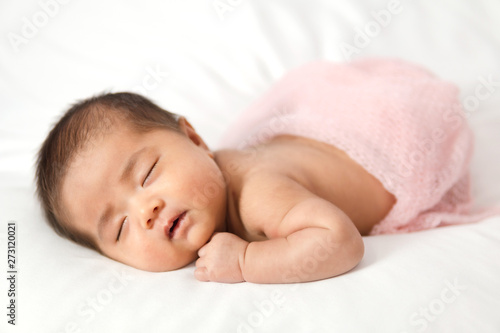 Adorable asian newborn baby in pink wrap sleeping on white blanket background.