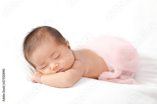 Adorable asian newborn baby in pink wrap sleeping on white blanket background.