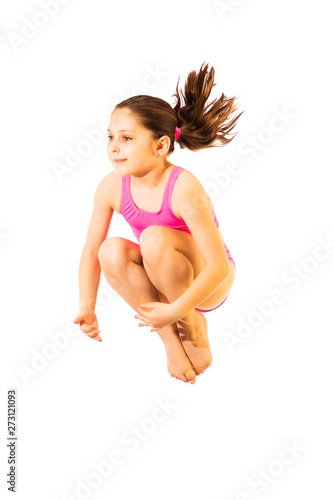 Little caucasian female 8 years old girl in pink swimmwear jumping on white background.