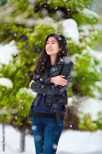 Slika na platnu Teen girl standing outdoors in winter snowfall  shivering from cold