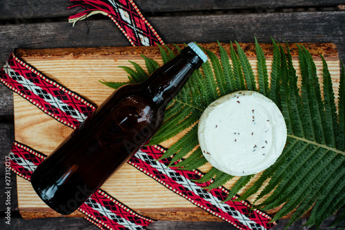 Latvian national beer and cheese on fern and with folk belt photo