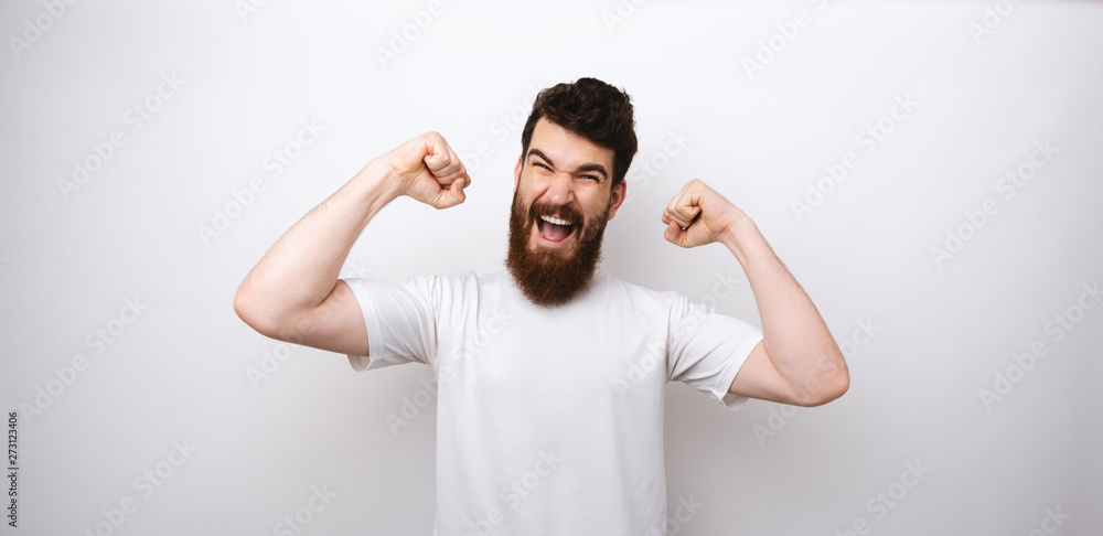 Young attractive bearded man making a winner gesture with his arms on white background. Young attractive bearded man making a winner gesture with his arms on white background.