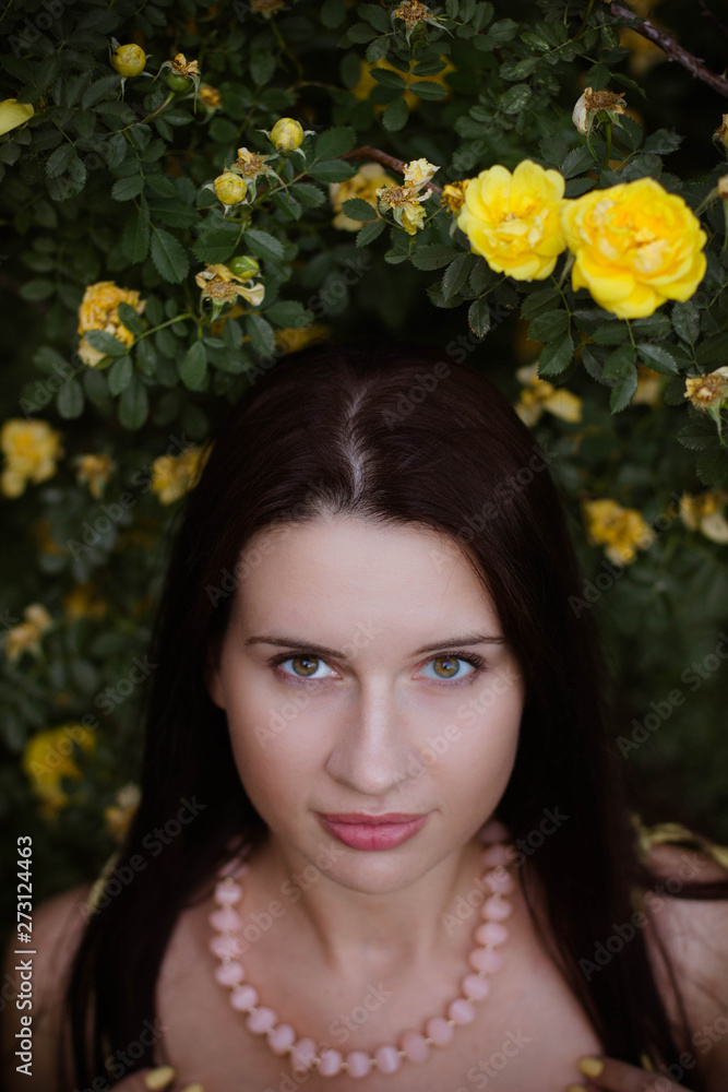 Naklejka premium portrait of a young girl in yellow rosehips