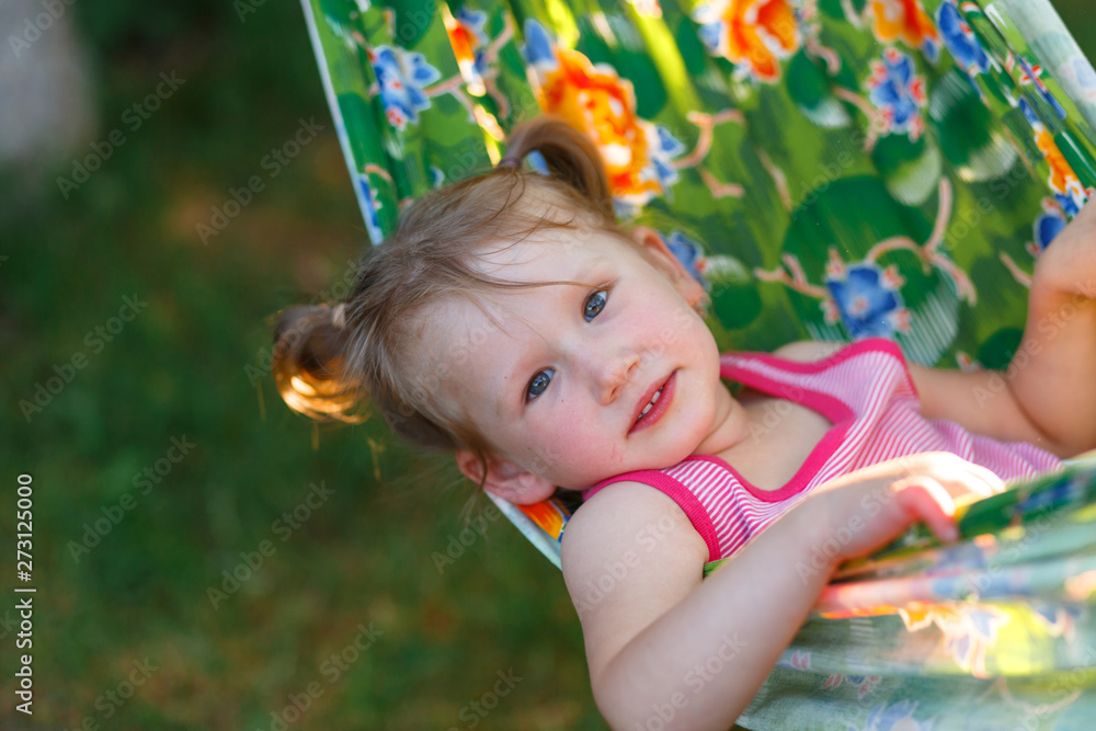 A little girl having fun in the hammock in summer at the sunset A little girl having fun in the hammock in summer at the sunset