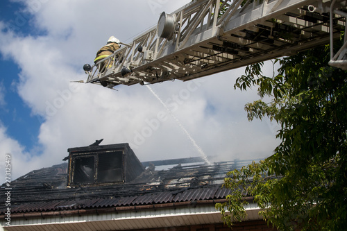 Smoldering remains of a ghetto house with a fireman spraying water photo